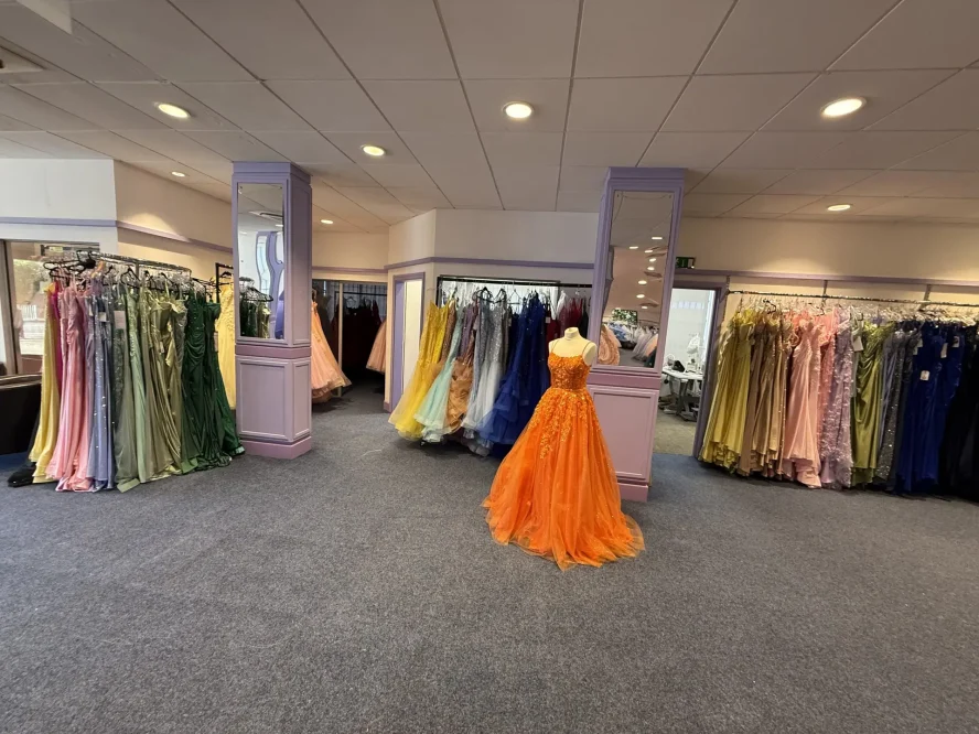 Real MK Prom showroom floor in Bletchley with colourful prom dresses and an orange ballgown on display